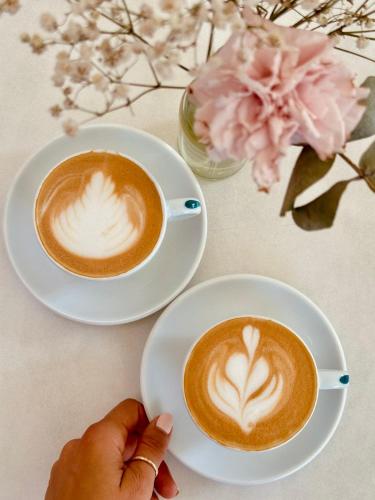 a person holding two cups of coffee on plates at THE NIXON Luxury Suites and Apartment Hotel in Athens