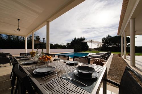 a dining table on a patio with a pool at Grande Setubal Villa 5 Bedrooms Villa Monte Maria Pratas in Setúbal