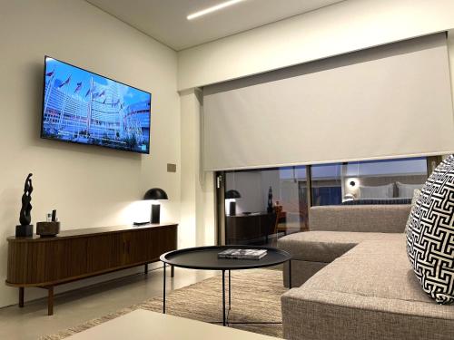 a living room with a couch and a tv on the wall at THE NIXON Luxury Suites and Apartment Hotel in Athens