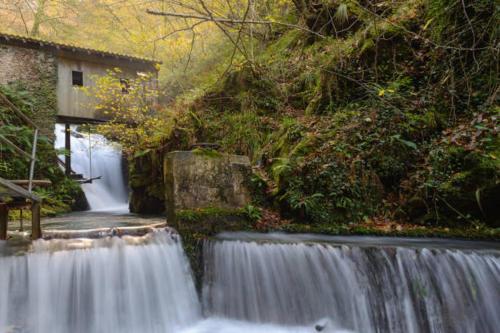 a waterfall in front of a house next to a river at Apartamento Larrazu II Agroturismo Baztán in Arráyoz