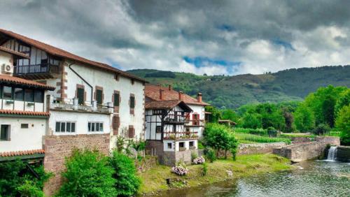 a group of buildings next to a river at Apartamento Larrazu II Agroturismo Baztán in Arráyoz