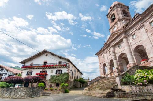 an old building with a clock tower in a town at Apartamento Larrazu II Agroturismo Baztán in Arráyoz