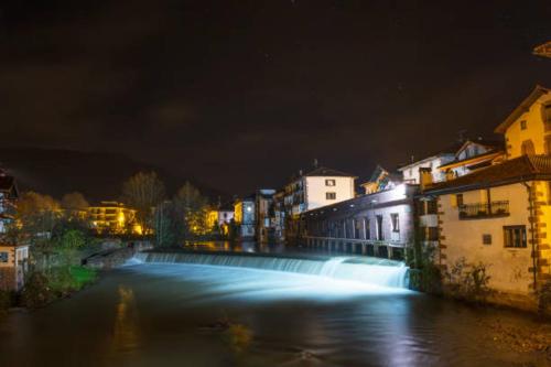 a bridge over a river in a city at night at Apartamento Larrazu II Agroturismo Baztán in Arráyoz