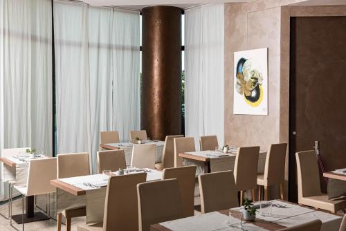 a dining room with tables and chairs and a painting on the wall at Phi Hotel Milano in Baranzate