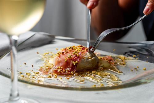 a person eating a dessert on a plate with a fork and knife at Phi Hotel Milano in Baranzate