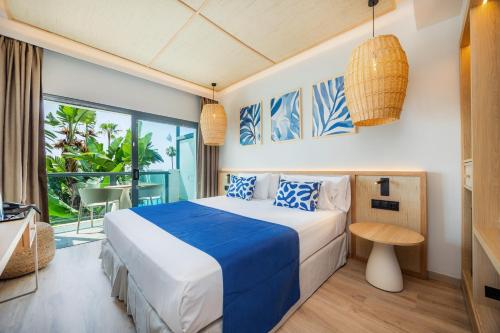 a bedroom with a blue and white bed and a balcony at Marins Suites - Adults Only Hotel in Cala Millor