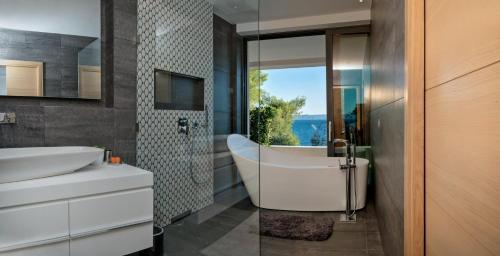 un bagno con vasca, lavandino e finestra di Villa Acona Selca Film Star Looks In A Glamorous Setting With Amazing Facilities Brac a Selca