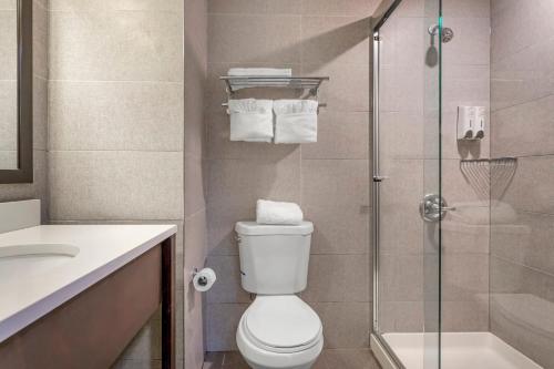 a bathroom with a toilet and a glass shower at Red Roof PLUS Brooklyn - 3rd Ave in Brooklyn