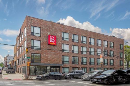 a large brick building with a red sign on it at Red Roof PLUS Brooklyn - 3rd Ave in Brooklyn