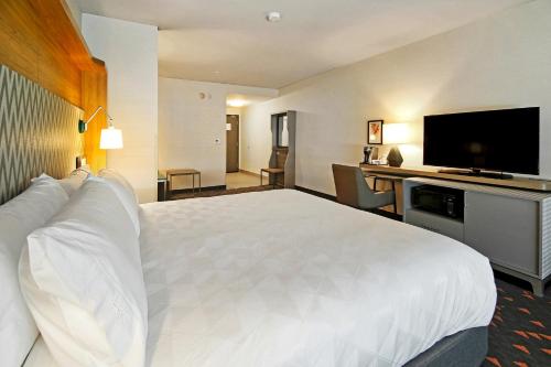 a hotel room with a large bed and a flat screen tv at Holiday Inn Hotel & Suites - Calgary Airport North by IHG in Calgary