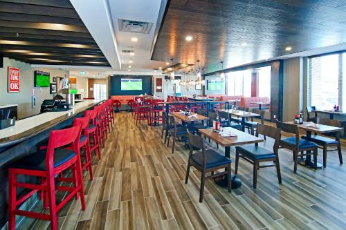 a restaurant with red chairs and tables and a bar at Holiday Inn Hotel & Suites - Calgary Airport North by IHG in Calgary