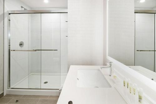 a white bathroom with a shower and a sink at Holiday Inn Hotel & Suites - Calgary Airport North by IHG in Calgary