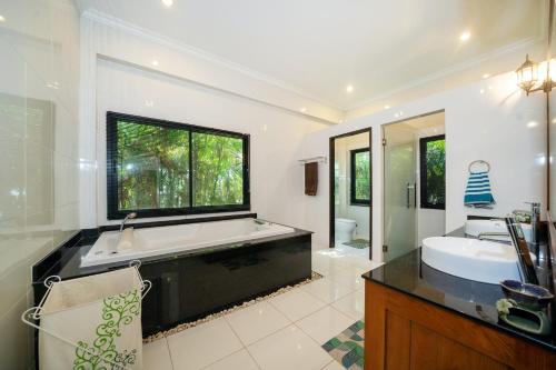 Un baño con una bañera grande y un lavabo. en Bua Sawan - 4 Bedrooms Pool Villa, en Ban Pak Lak