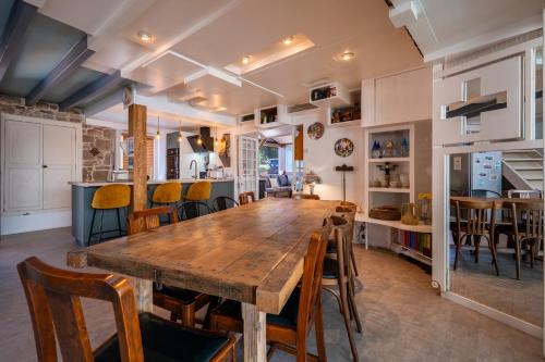 une cuisine et une salle à manger avec une table et des chaises en bois dans l'établissement Maison en pierre, piscine et jardin proche mer, à Montfarville