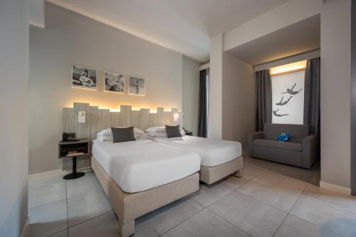 a bedroom with a large white bed and a chair at Nautilus Family Hotel in Pesaro