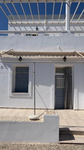 a white building with a blue door and a porch at Syros Rooms & Apartments in Posidhonía