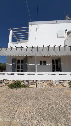 a white building with awning on the side of it at Syros Rooms & Apartments in Posidhonía