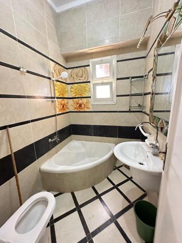 a bathroom with a tub and a toilet and a sink at فيلا اول صف بحر مارينا الساحل الشمالي العلمين برايفت بول in El Alamein