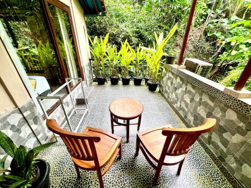 a balcony with two chairs and a table and some plants at Guesthouse Gusti Putu Oka in Ubud