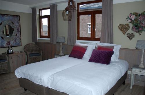 a bedroom with a large white bed with purple pillows at Bed en Breakfast VerdeSud in Eijsden