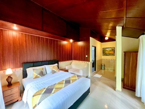 a bedroom with a bed and a wooden wall at Guesthouse Gusti Putu Oka in Ubud