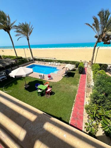 a backyard with a swimming pool and the beach at فيلا اول صف بحر مارينا الساحل الشمالي العلمين برايفت بول in El Alamein