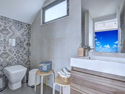 un bagno con lavandino, WC e finestra di Villa Limni Dyo - Luxurious Contemporary 3 Bedroom Villa With Sea Views And Hot Tub a Paralimni