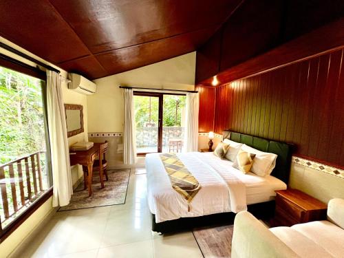 a bedroom with a bed and a balcony with a desk at Guesthouse Gusti Putu Oka in Ubud