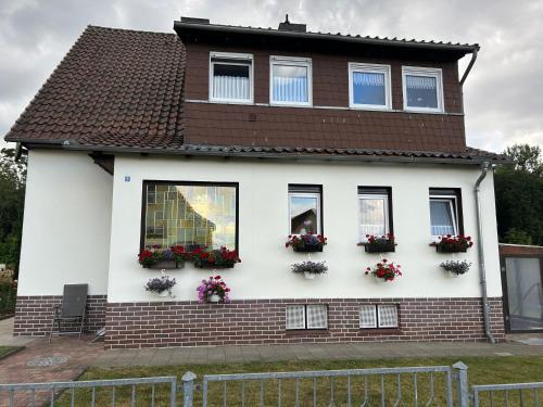a white house with flowers in windows at Ferienwohnung Winzenburg Natur nah und ruhig gelegene Ferienwohnung nah am Steinhuder Meer und Dinopark Münchehagen in Rehburg-Loccum