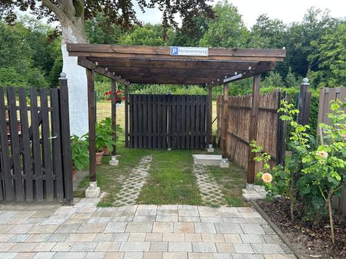 a wooden pergola in a garden with a fence at Ferienwohnung Winzenburg Natur nah und ruhig gelegene Ferienwohnung nah am Steinhuder Meer und Dinopark Münchehagen in Rehburg-Loccum