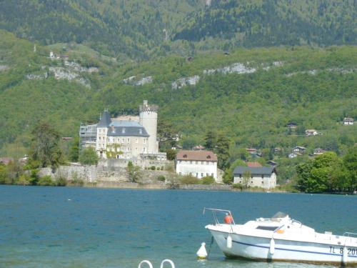a boat sitting in the water in front of a castle at la baie des voiles ,vue lac d'Annecy ,plage privée in Duingt