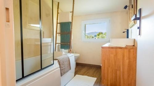 Elle comprend une petite salle de bains pourvue de toilettes et d'une fenêtre. dans l'établissement Chambre Canopée - maison exotique, à Hyères