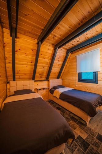 two beds in a wooden room with a window at Sapanca Özfer Bungalov in Sapanca