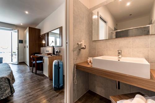 a bathroom with a white sink and a bedroom at Hotel National in Zelbio