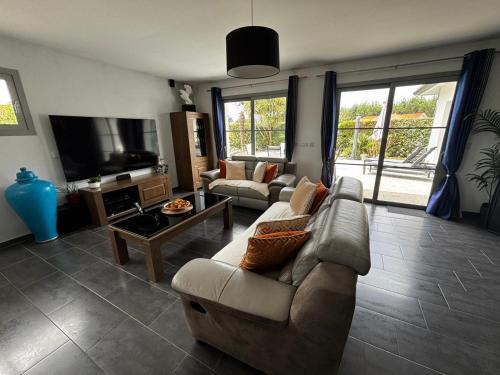 a living room with a couch and a tv at Superbe villa 6 personnes proche océan et lac in Linxe