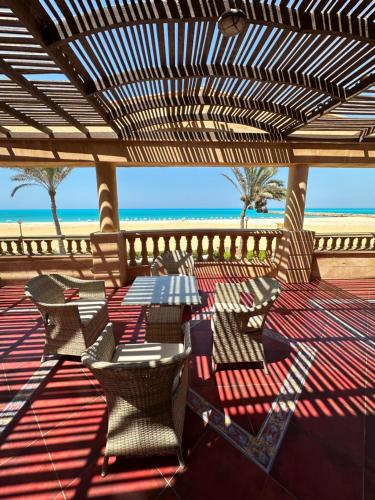 a patio with a table and chairs on the beach at فيلا اول صف بحر مارينا الساحل الشمالي العلمين برايفت بول in El Alamein