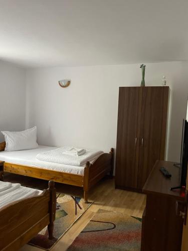 a bedroom with two beds and a wooden cabinet at Pensiunea Delia in Izlaz