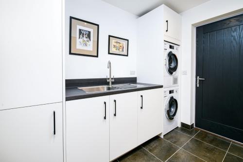 a kitchen with white cabinets and a black door at The Cotswold Light House ML63 Lower Mill Estate in Somerford Keynes