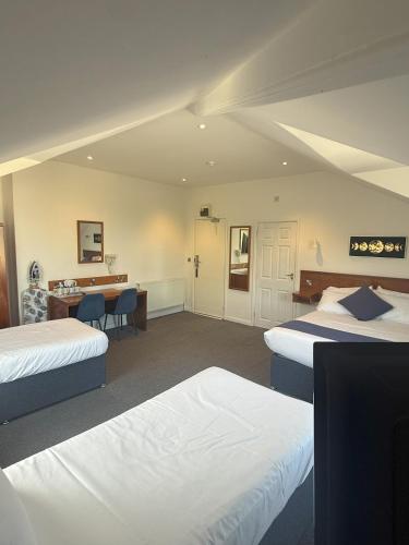 a hotel room with two beds and a desk at Chase Hotel in Whitehaven
