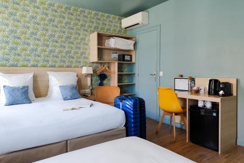 a hotel room with two beds and a desk at Hôtel Du Centre, un hôtel AMMI in Nice
