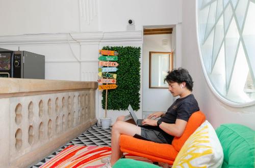 a woman sitting in an orange chair with a laptop at Urban Hostel Palma - Albergue Juvenil - Youth Hostel in Palma de Mallorca