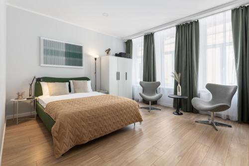 a bedroom with a bed and two chairs and windows at P6-A Riga Old Town Apartments in Rīga