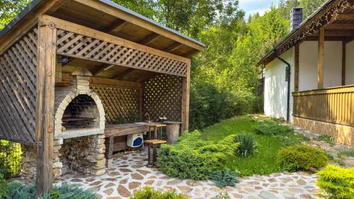 a wooden pavilion with a stone oven in a garden at Locul cu Amintiri in Albac