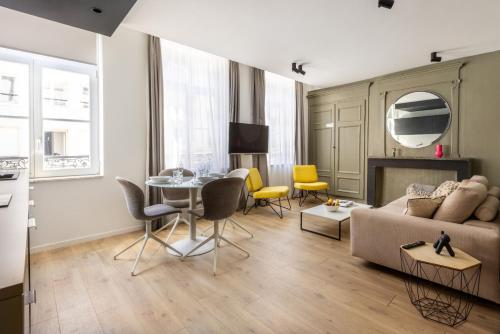 un salon avec un canapé, une table et des chaises dans l'établissement Au Chat Qui Dort Lille - Archives 3, à Lille