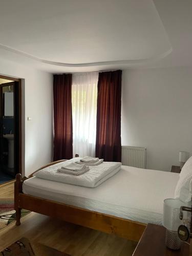 a bedroom with a bed with white sheets and a window at Pensiunea Delia in Izlaz