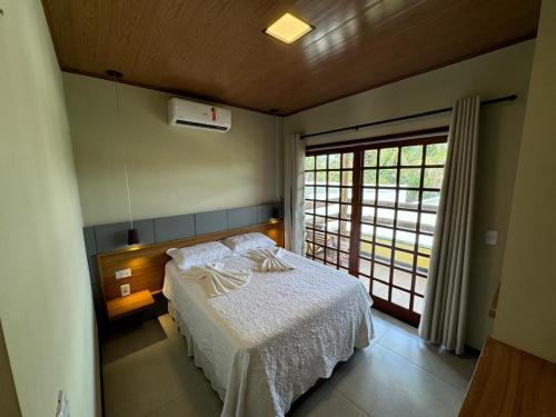 a bedroom with a bed and a large window at Vila dos Poetas - 02 quartos - GD in Barreirinhas