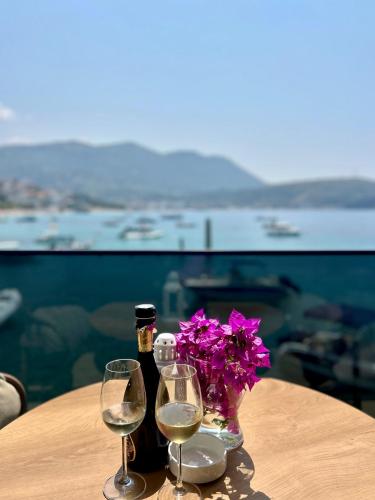 a table with two glasses and a bottle of wine and flowers at Rea Boutique Hotel in Himare