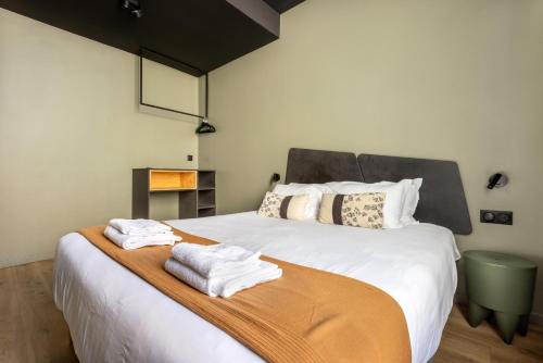 a bedroom with a large white bed with towels on it at Au Chat Qui Dort Lille - Archives 3 in Lille