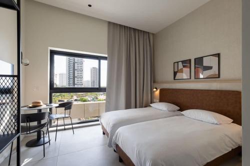 a hotel room with a bed and a desk and a window at Tayo Studios & Apartments in Bat Yam
