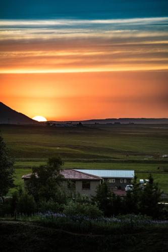 a house in a field with the sunset in the background at Breidamyri Farm Apartments in Laugar